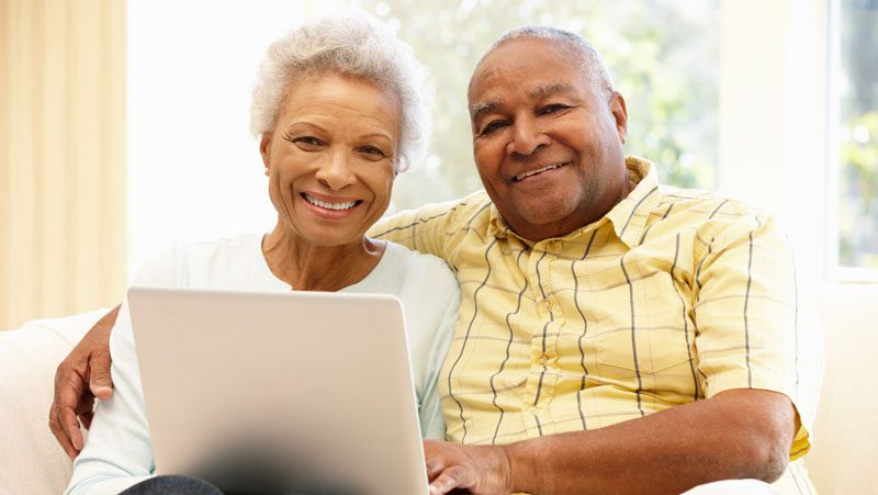 Senior couple smiling over a laptop