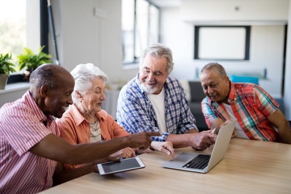 Group of senior citizens smiling while looking at a laptop
